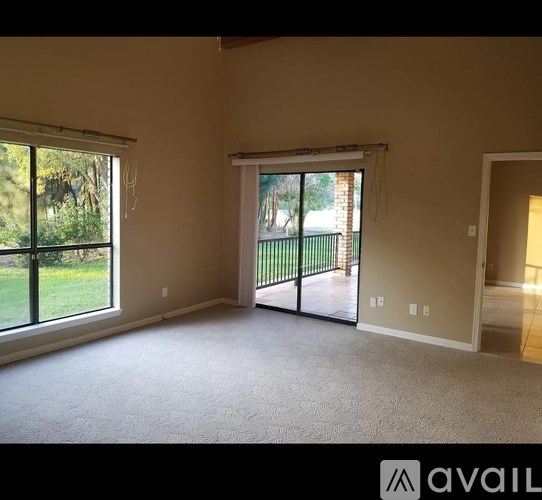 A spacious room with a sliding glass door leading to a balcony.