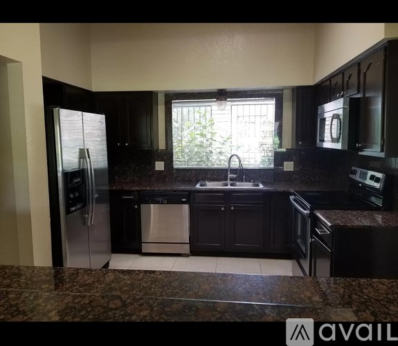 A kitchen with black cabinets and a granite countertop.