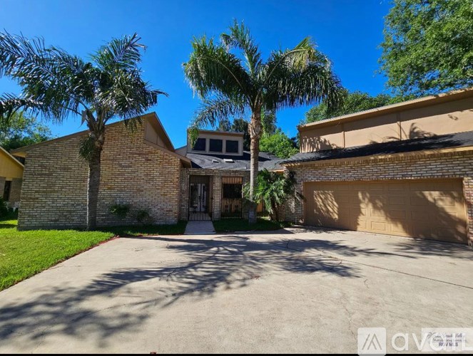 A house with a driveway and palm trees in front.