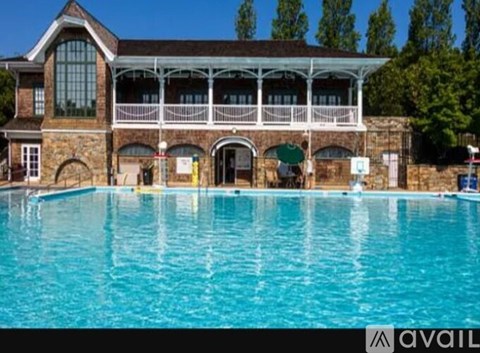 A large swimming pool in front of a building with a balcony.