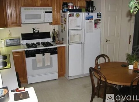 A kitchen with a white refrigerator, wooden cabinets, and a black stove top.