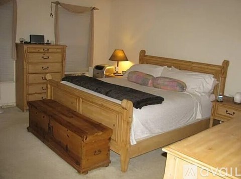 A bedroom with a bed, nightstand, and a wooden chest.