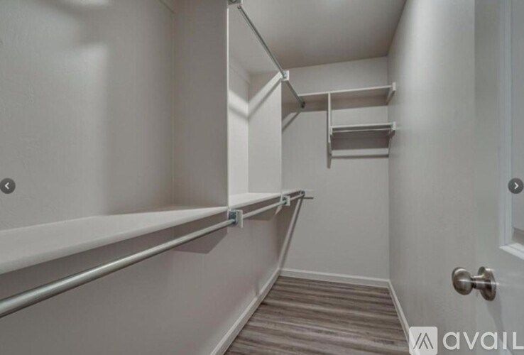 A hallway with a door on the right and a shelving unit on the left.