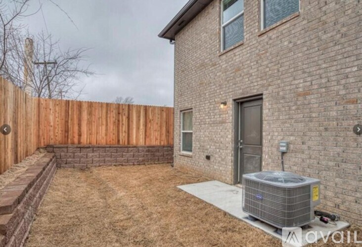 A backyard with a wooden fence and a brick house.