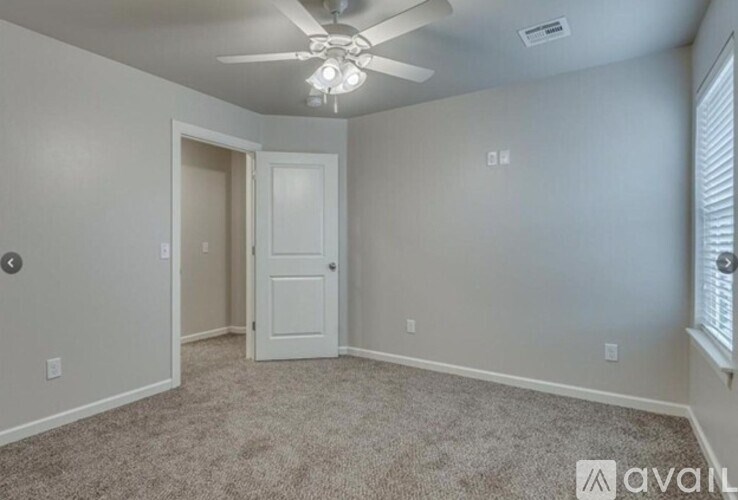 A room with a carpeted floor and a ceiling fan.