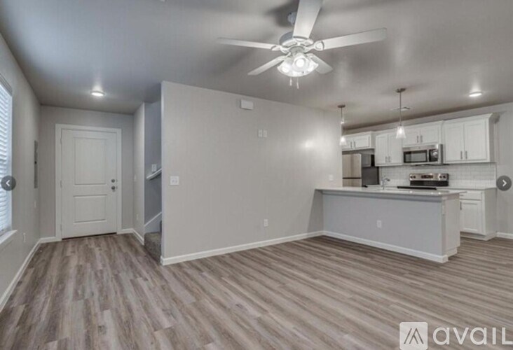 A spacious room with a kitchenette and a staircase.