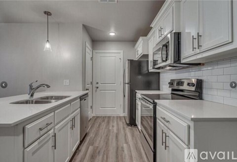 A kitchen with white cabinets and a wooden floor.