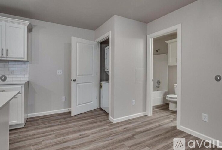 A kitchen with white cabinets and a wooden floor.