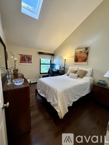A bedroom with a bed, nightstand, and a window with a view of the backyard.