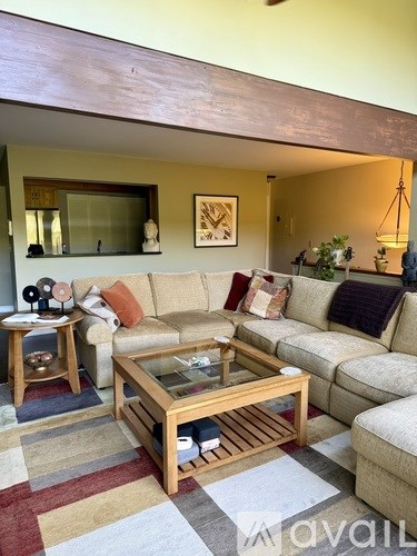 A living room with a couch, a coffee table, and a rug.