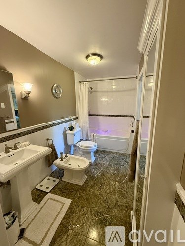 A bathroom with a marble floor and a toilet in the background.