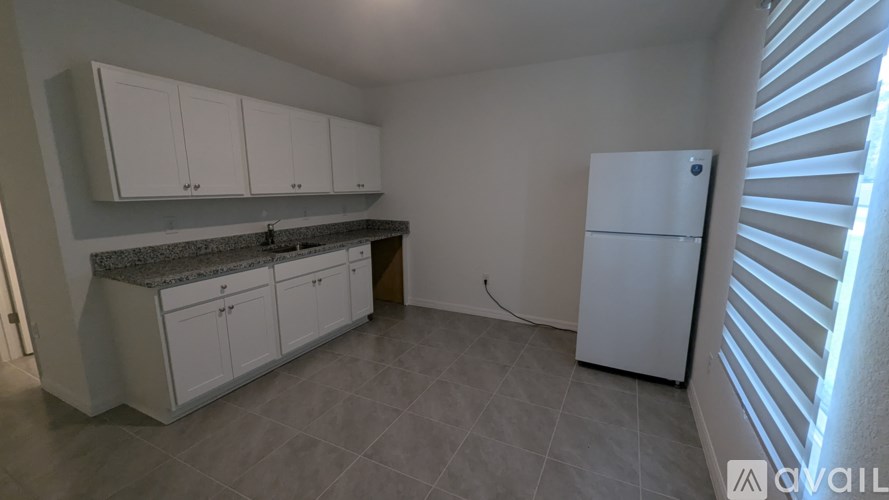 A kitchen with white cabinets and a white refrigerator.