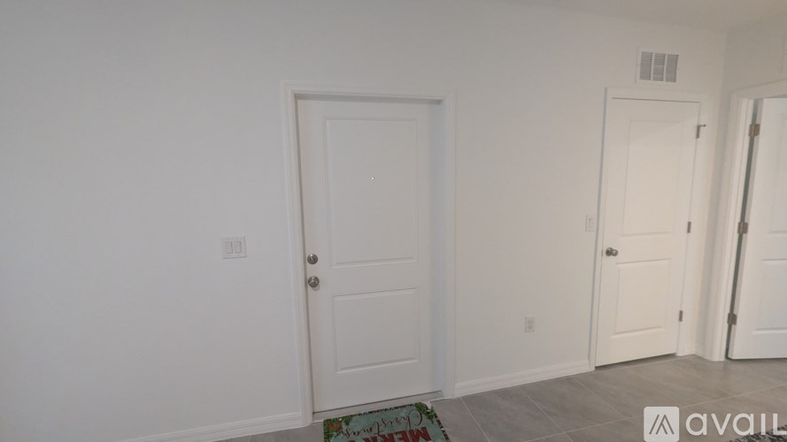 A room with two doors and a mat on the floor.