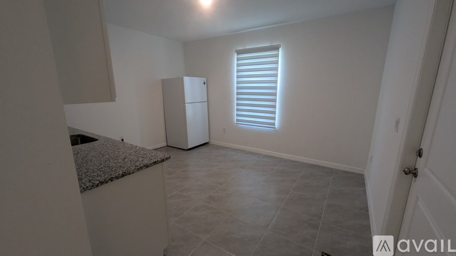A room with a granite countertop and a white fridge.