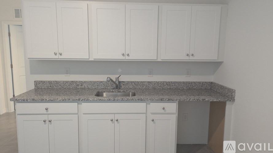 A kitchen with granite countertops and white cabinets.