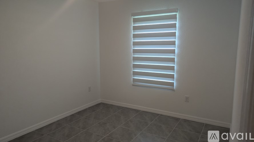 A room with a window covered by horizontal blinds.