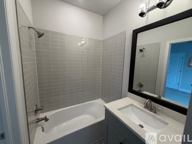 A bathroom with a white tub and a sink with a mirror above it.