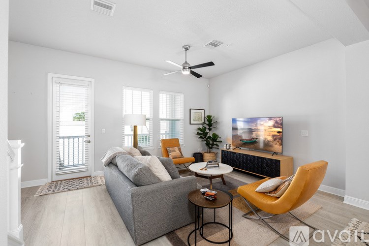 A living room with a grey couch, a yellow chair, a small table, and a television.