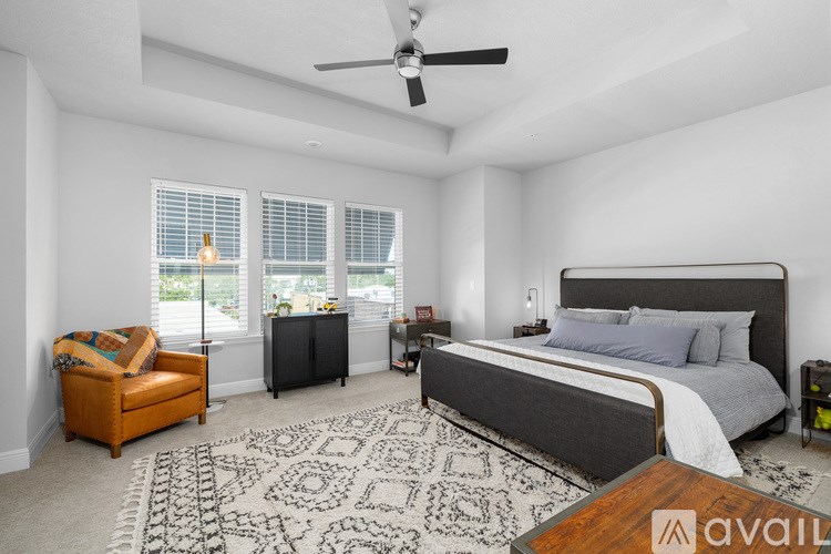 A bedroom with a large bed, a chair, and a rug.