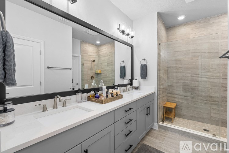 A bathroom with a large mirror, a sink, and a shower.