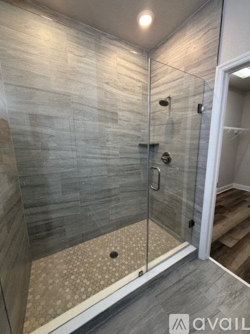 A bathroom with a toilet, a glass shower stall, and a towel bar.