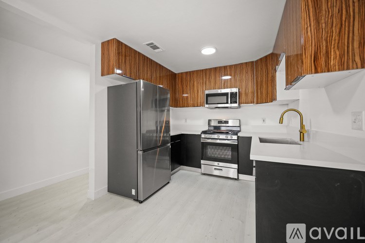 A kitchen with a refrigerator, microwave, oven, and sink.