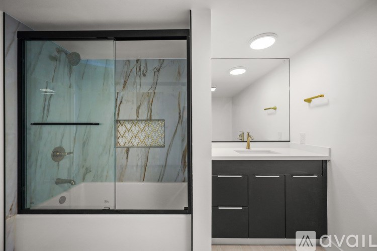 A bathroom with a marble patterned shower and a sink with a cabinet.