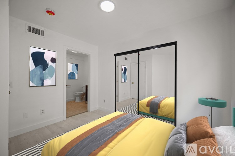 A bedroom with a bed in the center and a mirror on the wall.