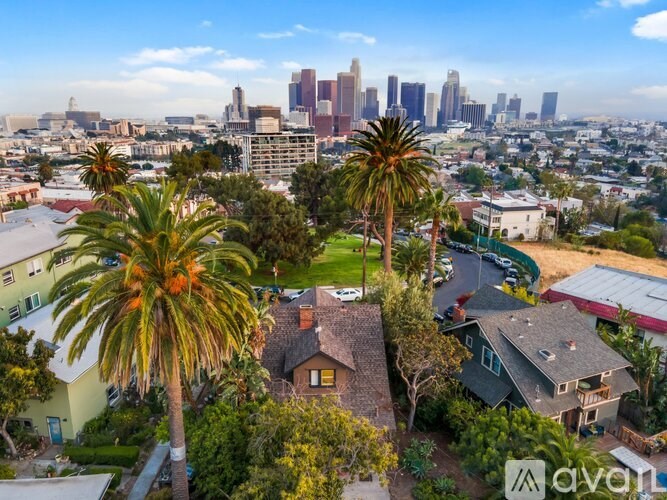 A house with palm trees in front and a city skyline in the background.