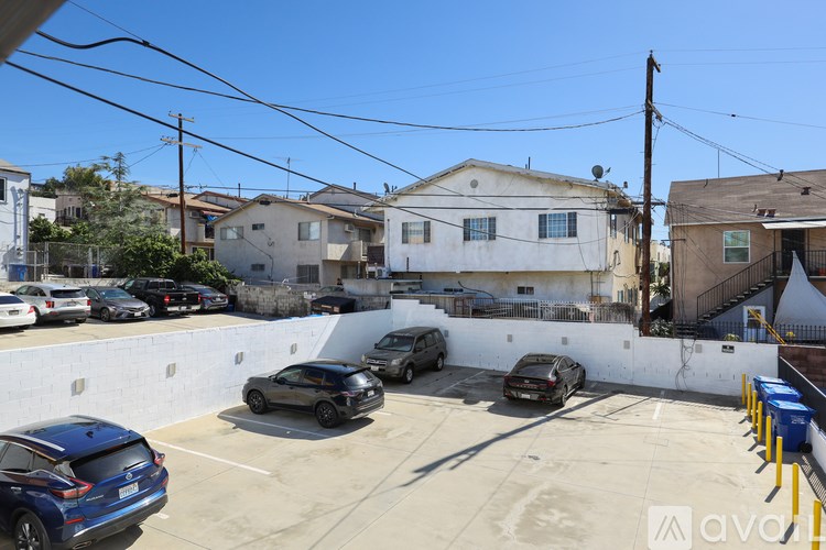 A parking lot with cars and houses in the background.