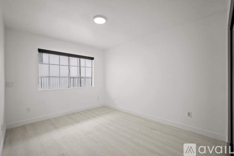 A spacious room with a window and wooden flooring.