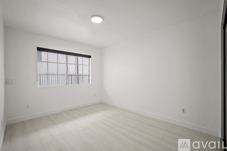 A spacious room with a window and wooden flooring.