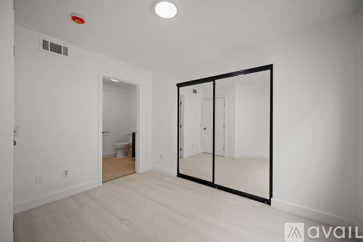 A large empty room with a mirror and a red light on the ceiling.
