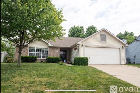 A house with a garage and a tree in front.