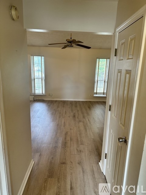 A room with a ceiling fan and wooden flooring.