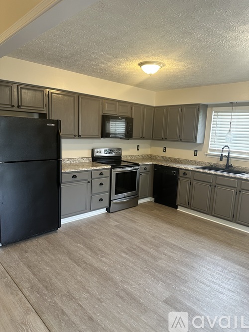A kitchen with black appliances and wooden cabinets.