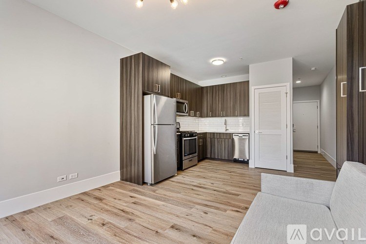 A modern kitchen with wooden floors and stainless steel appliances.