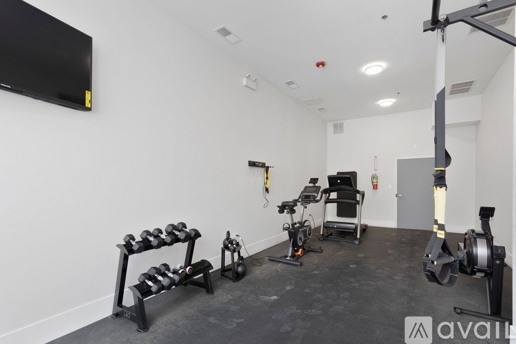 A gym with a variety of equipment including a rowing machine, a stationary bike, and a bench press.