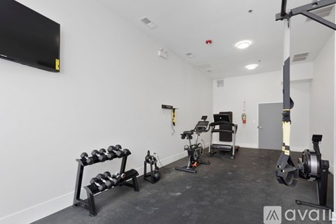 A gym with a variety of equipment including a rowing machine, a stationary bike, and a bench press.