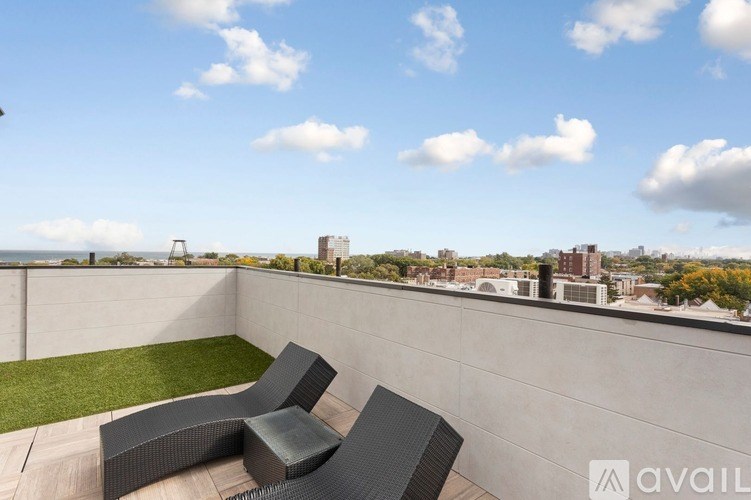 A patio with two black chairs and a table overlooking a cityscape.