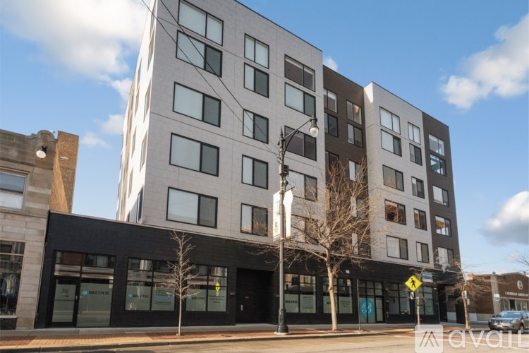 A modern multi-story building with a black awning and glass windows.