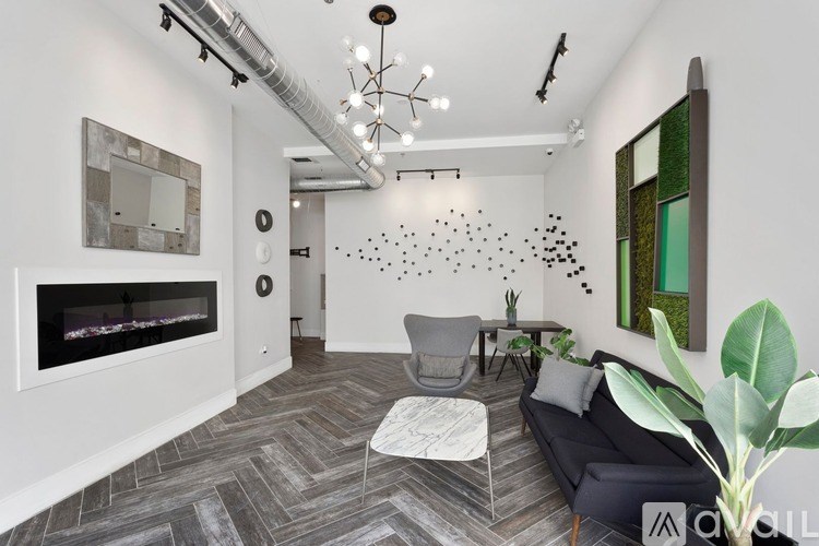 A modern living room with a grey couch, a white coffee table, and a fireplace with a mirror above it.