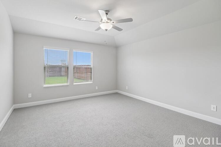 A spacious room with a ceiling fan and two windows.