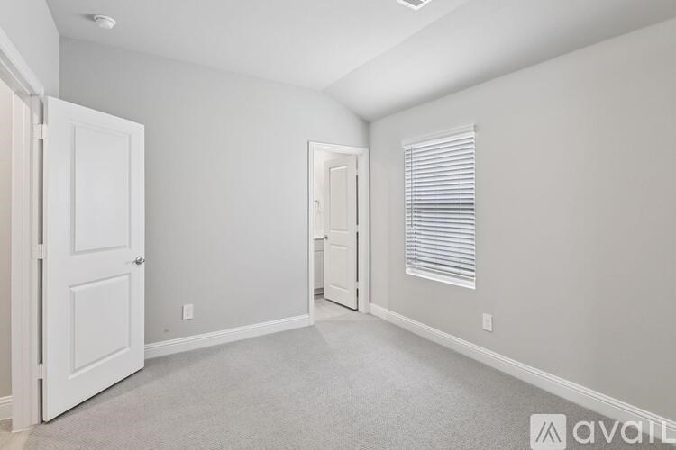 A room with a carpeted floor and two doors.