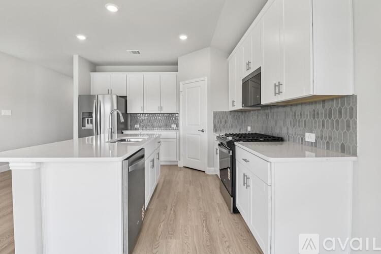 A modern kitchen with white cabinets and a wooden floor.