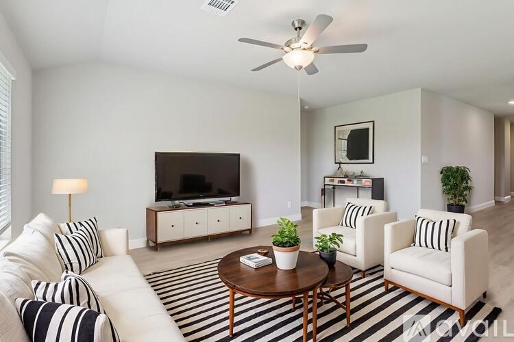 A living room with a white couch, a coffee table, and a television.