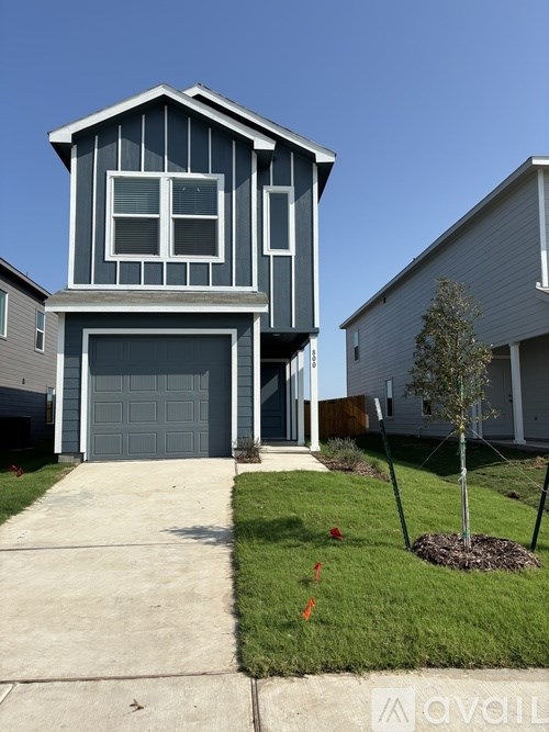 A two-story house with a garage and a tree in front.
