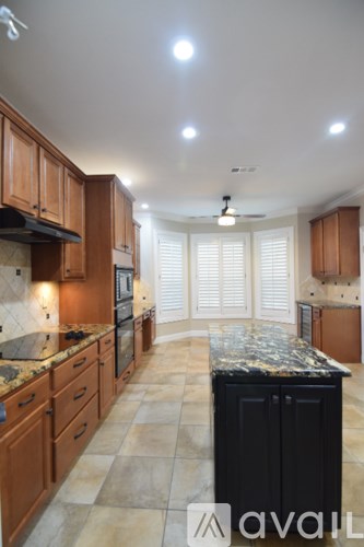 A kitchen with wooden cabinets and a black island.
