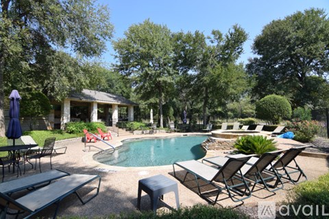 A pool surrounded by chairs and trees.