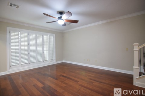 A room with a ceiling fan and wooden floors.